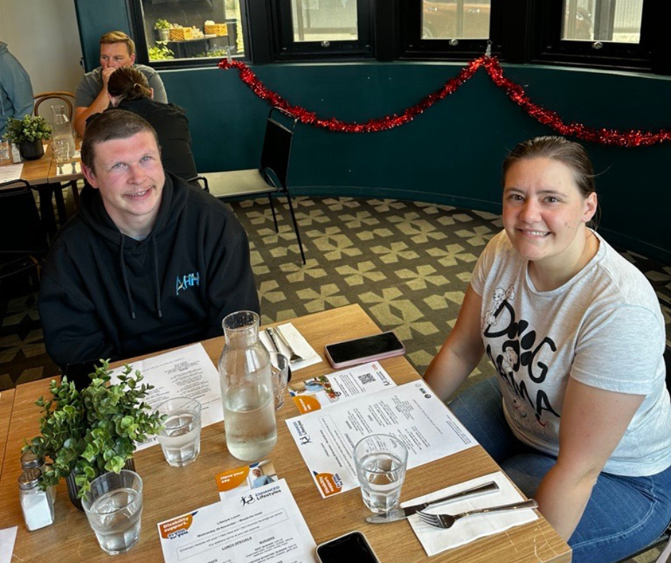 Two people smiling at a table at a restaurant.