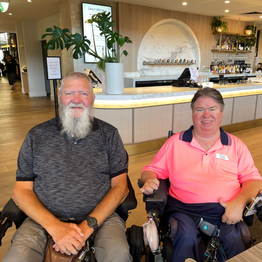 Two people in wheelchairs sitting at a table in a restaurant.