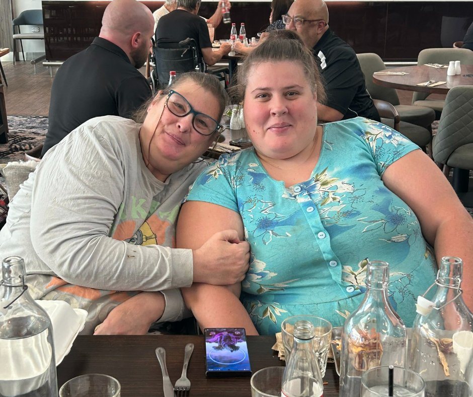 Two women posing for a picture at a restaurant.