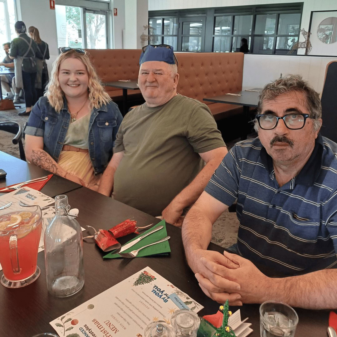 Three people seated at a table with drinks, a menu, and holiday decorations in a restaurant setting.