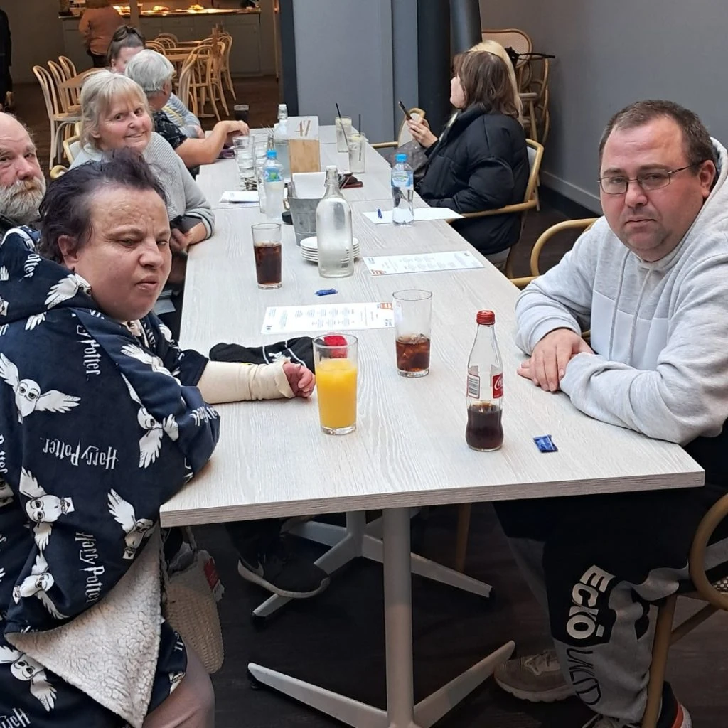 A group of people sitting around a table at a restaurant, with drinks and menus in front of them.