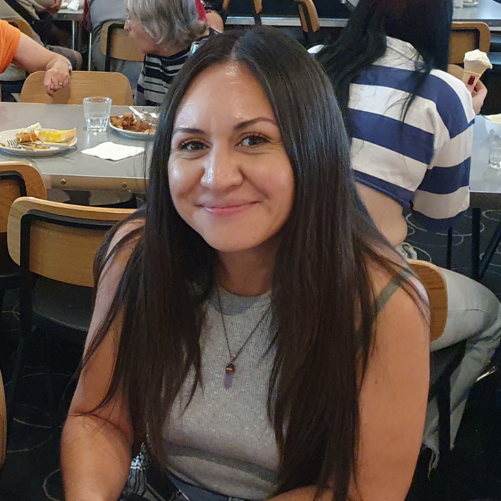 Woman smiling at the camera in a restaurant setting.