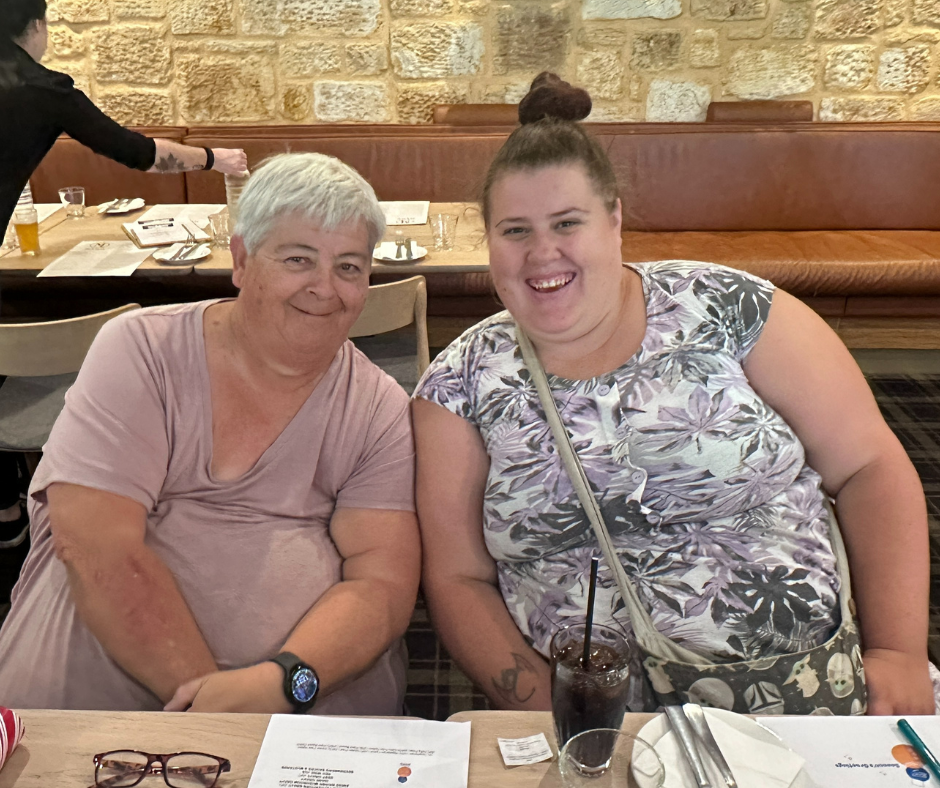 Two women smiling at a table in a restaurant.