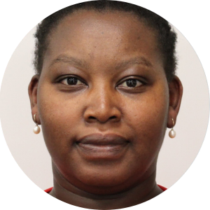 A woman wearing a red shirt and pearls.