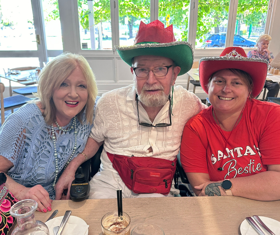 Three people sitting at a table wearing santa hats.