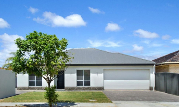 A house with a driveway and a tree in front of it.