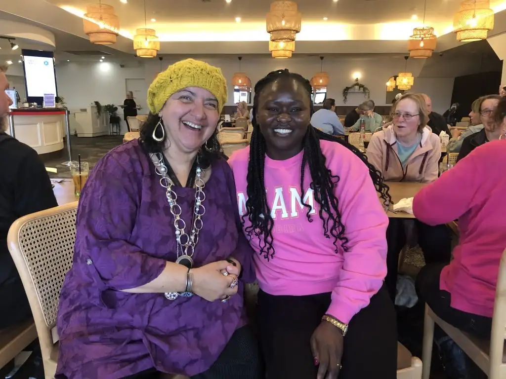 Two women smiling at each other in a restaurant.