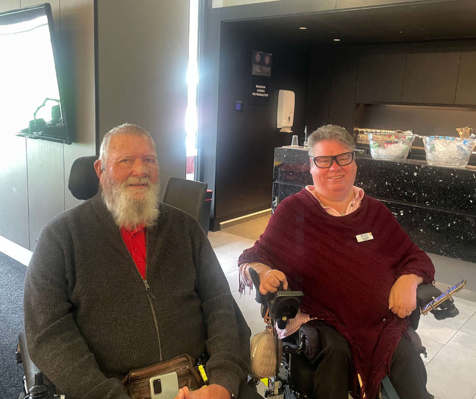 Two people in wheelchairs sitting in a lobby.