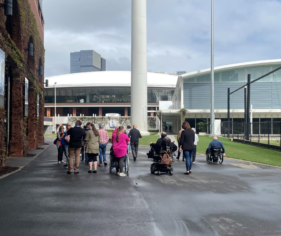 A group of people walking in front of a stadium.