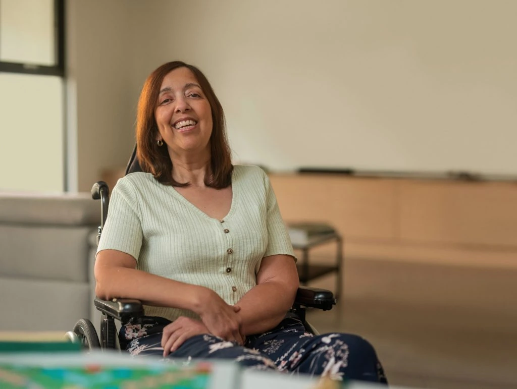 A woman in a wheelchair smiling in front of a board game.