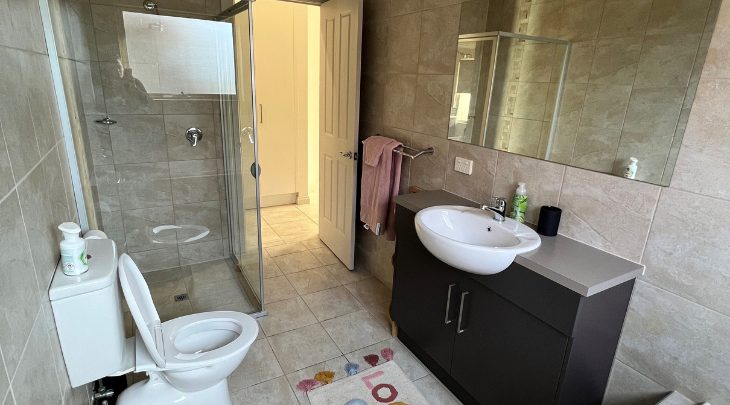 A bathroom with a toilet, sink and shower.