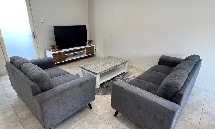 A living room with two grey couches and a tv.