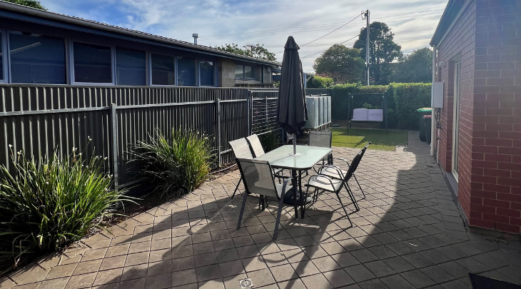 A backyard with a table and chairs and a fence.