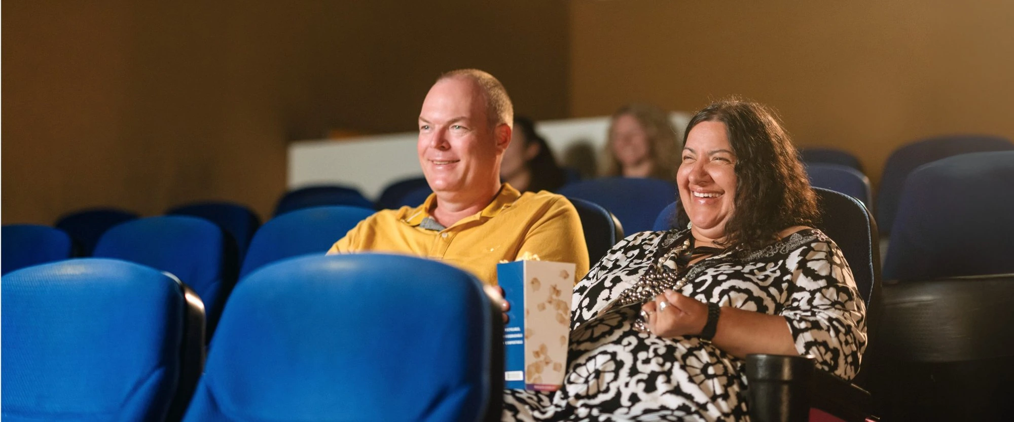 A man and woman sitting in a movie theater - NDIS Community Support