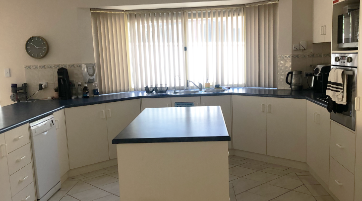 A kitchen with white counter tops and white appliances.