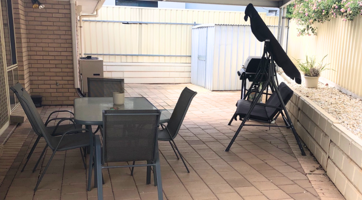 A patio with a table and chairs and an umbrella.