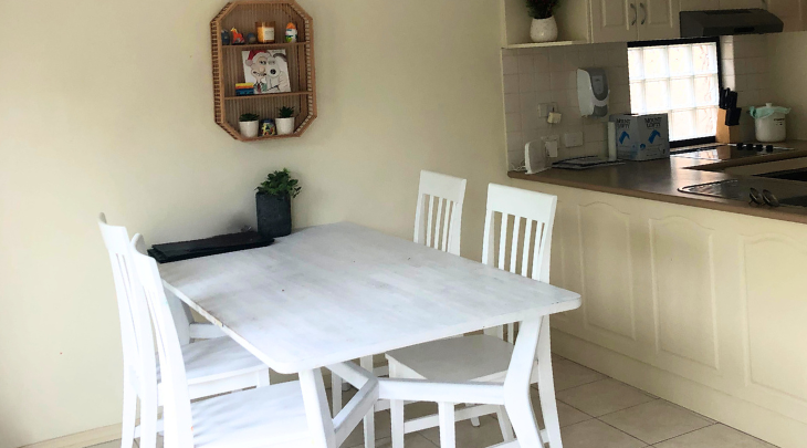 A small kitchen with a white table and chairs.