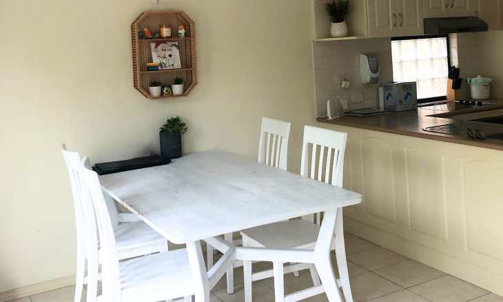 A small kitchen with a white table and chairs.