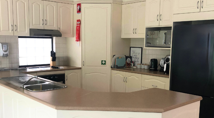 A kitchen with white cabinets and a refrigerator.