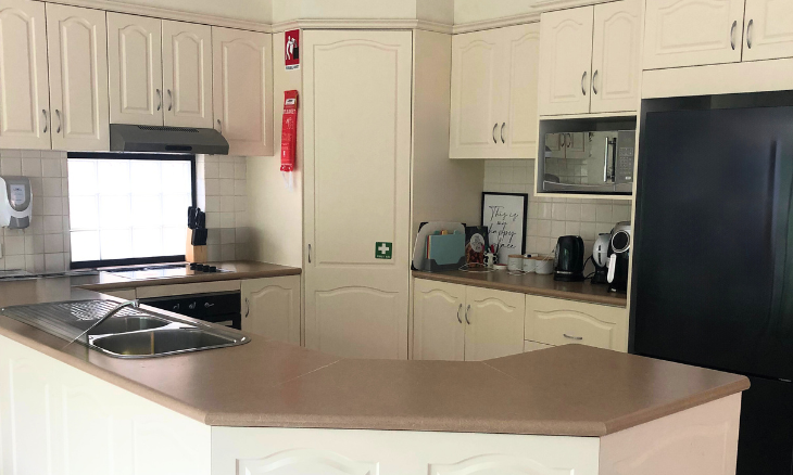 A kitchen with white cabinets and a refrigerator.