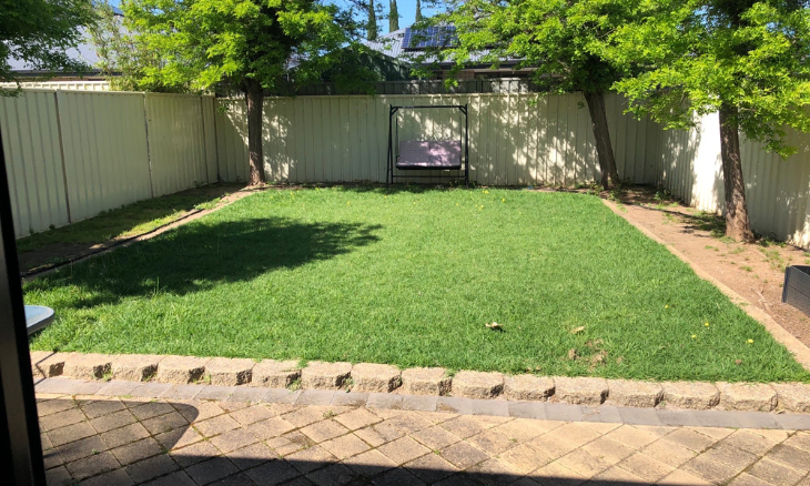 A backyard with grass and a fence.