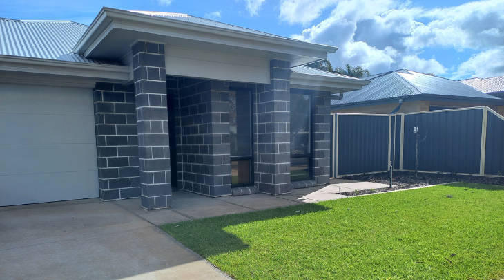 A house with a fence and grass in front of it.