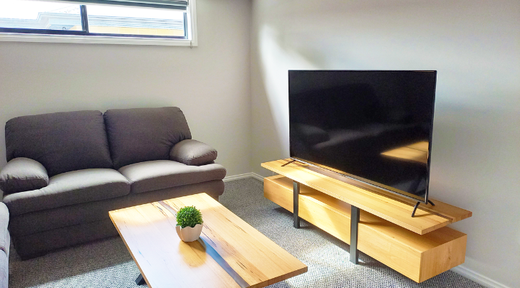 A living room with a couch, coffee table and tv.