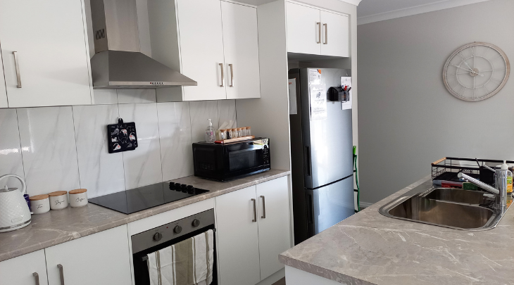 A kitchen with white cabinets and a microwave.