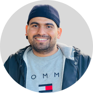 A smiling man wearing a hat and a t - shirt.