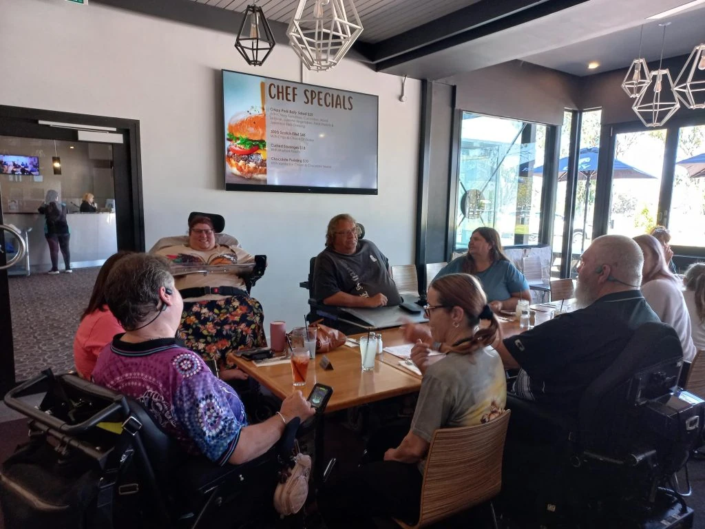 A group of people in wheelchairs sitting around a table.