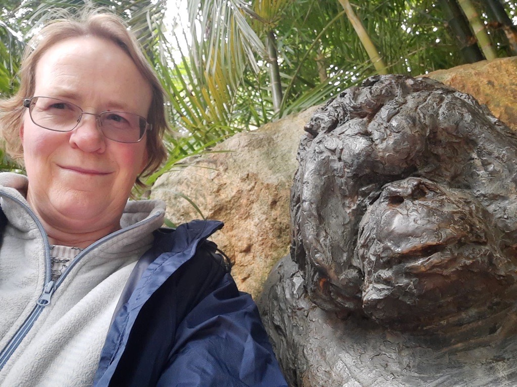 A woman is standing next to a statue of a gorilla at Adelaide Zoo.