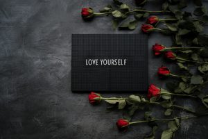 A black box with red roses and the word love yourself on it.