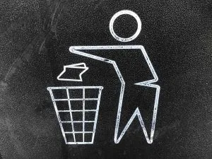 A man throwing a paper into a trash can.