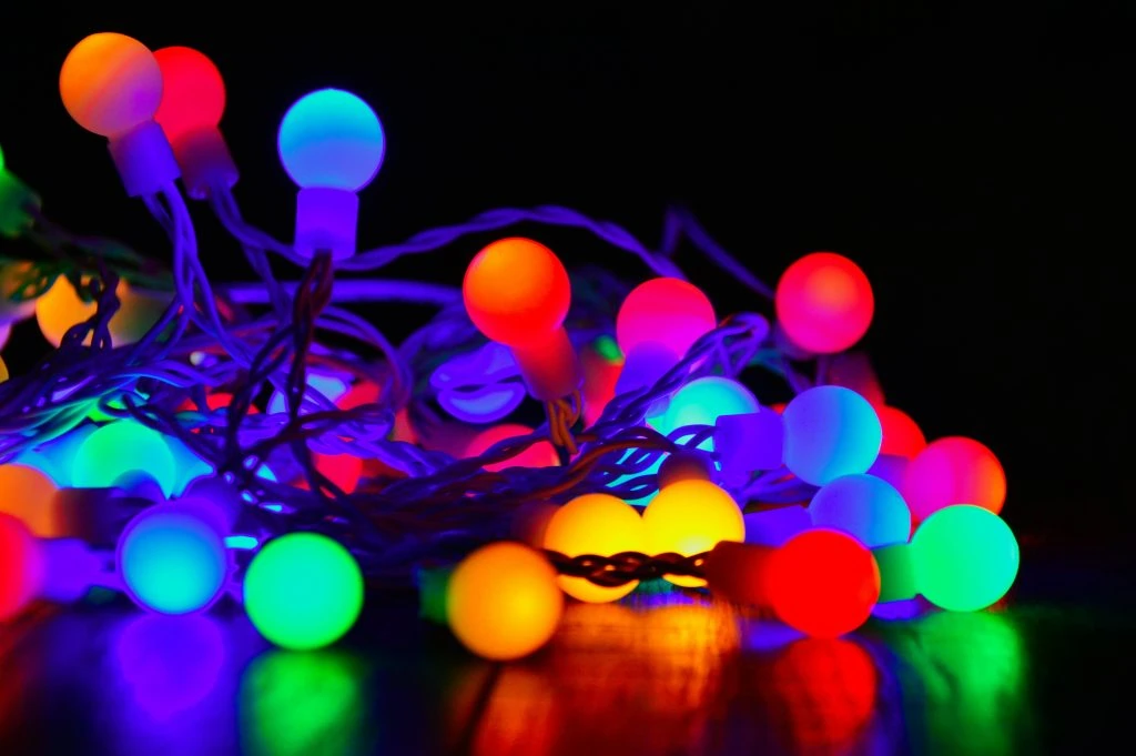 A tangle of colorful, glowing string lights against a dark background.