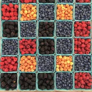 A variety of berries are arranged in baskets.