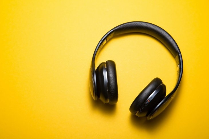 Black over-ear headphones on a bright yellow background.