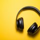 Black over-ear headphones on a bright yellow background.
