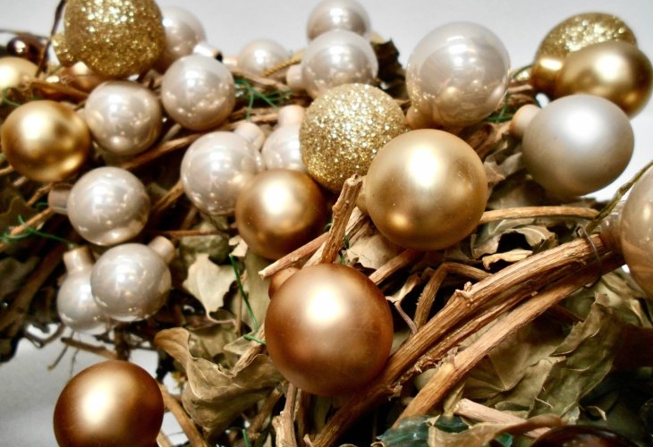 Golden and pearl-colored ornaments clustered with dried leaves and twigs.