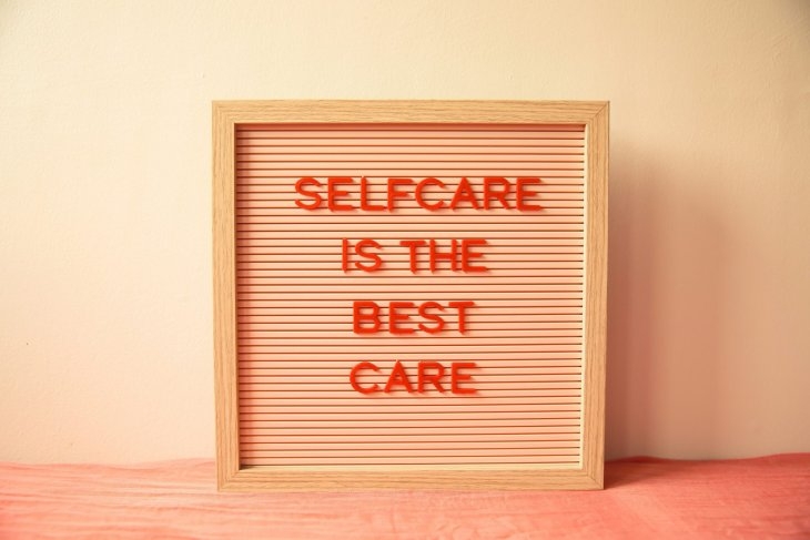 A framed letter board with the message "Selfcare is the best care" in red letters against a peach background.