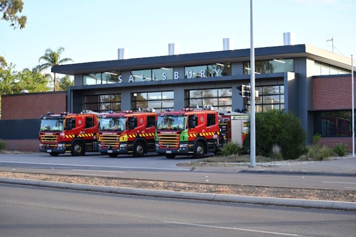 A group of fire trucks parked in front of a fire station.