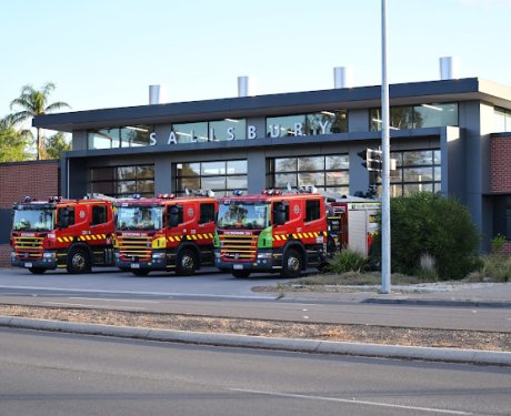 A group of fire trucks parked in front of a fire station.