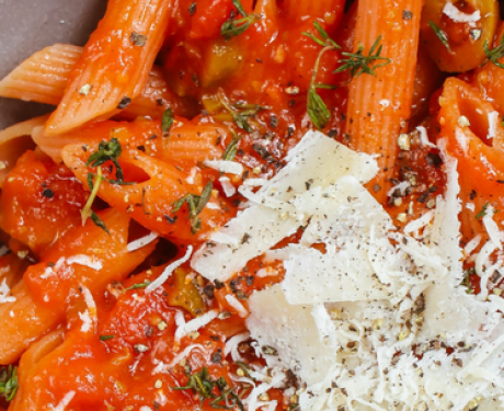 A bowl of pasta topped with tomatoes and parmesan.