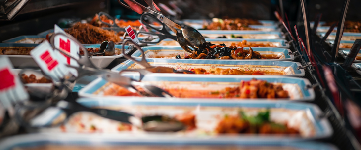 Many trays of food in a buffet line.