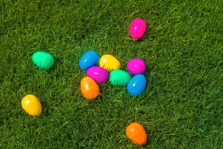 Colorful plastic easter eggs scattered on green grass.