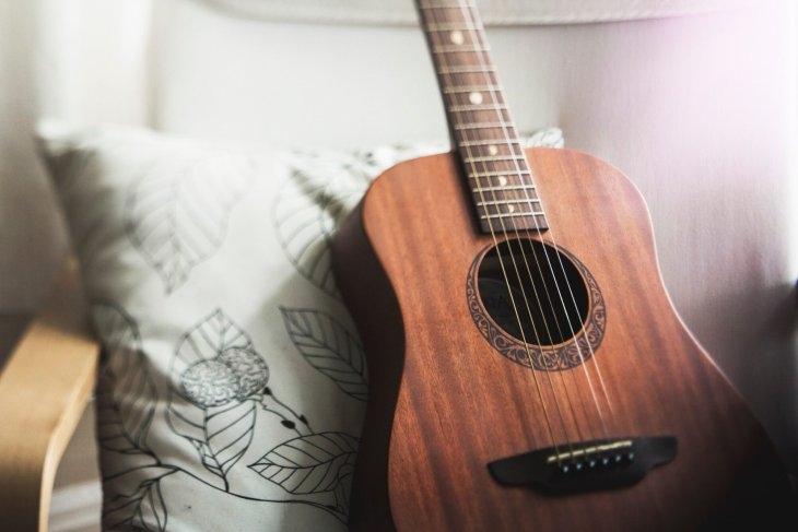 Image of an acoustic guitar on a chair with a cushion behind it - Music therapy