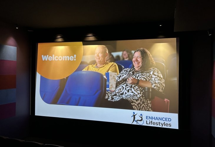 A photo of a movie screen that features a man and a woman watching a movie.