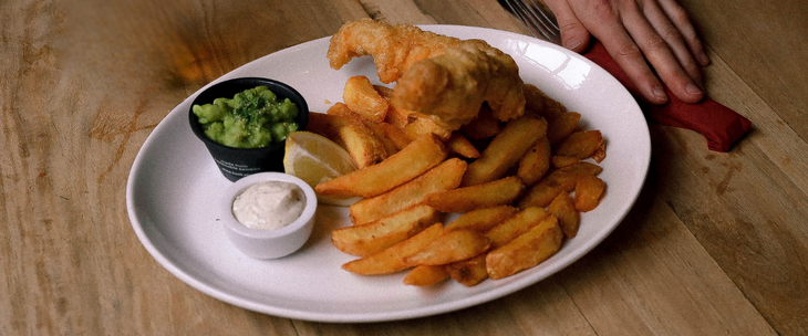 A plate of fish and chips presented on a rustic wooden table.