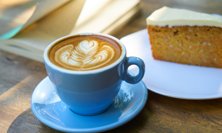 A cup of coffee and a slice of cake on a table.