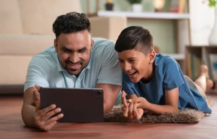 A man and a boy laying on the floor looking at a tablet | Downsides of too much screen time
