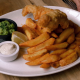 A plate of fish and chips on a wooden table.